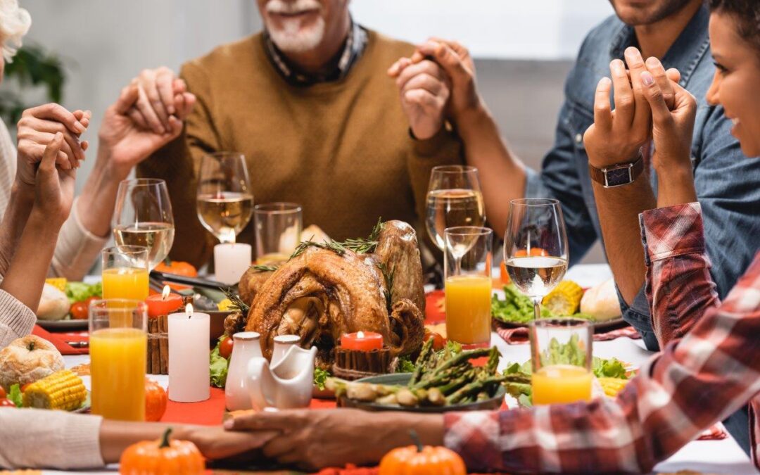 pleased multiethnic family holding hands on thanksgiving