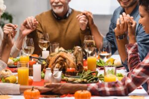 pleased multiethnic family holding hands on thanksgiving